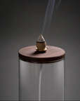 Incense cone burning on a glass stand with a dark background