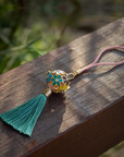Zen Aroma Flora Bloom Sachet Pendant with golden filigree cage, enamel floral design, and green silky tassel — crafted to hold up to two aroma pellets, blending fragrance with ornamental charm.