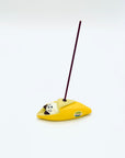 Cat & Banana incense holder in use, holding a burning incense stick upright from the banana peel.