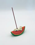 Cat & Watermelon incense holder in use with a lit incense stick standing upright.