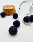 Close-up of Zen Aroma aroma pellets spilling from a glass jar with a cork lid, showcasing their natural texture and rich earthy color on a light background.