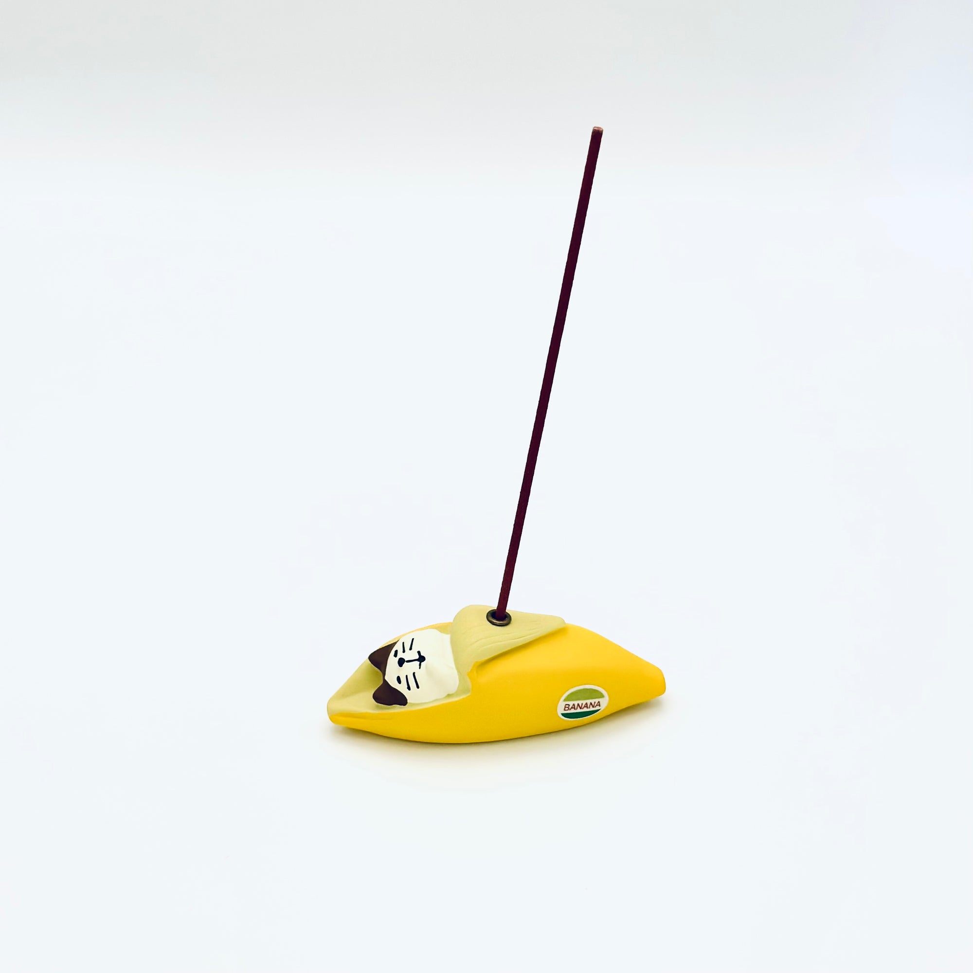 Cat & Banana incense holder in use, holding a burning incense stick upright from the banana peel.