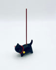 Cat & Bell incense holder in use, holding a lit short incense stick against a soft white background.