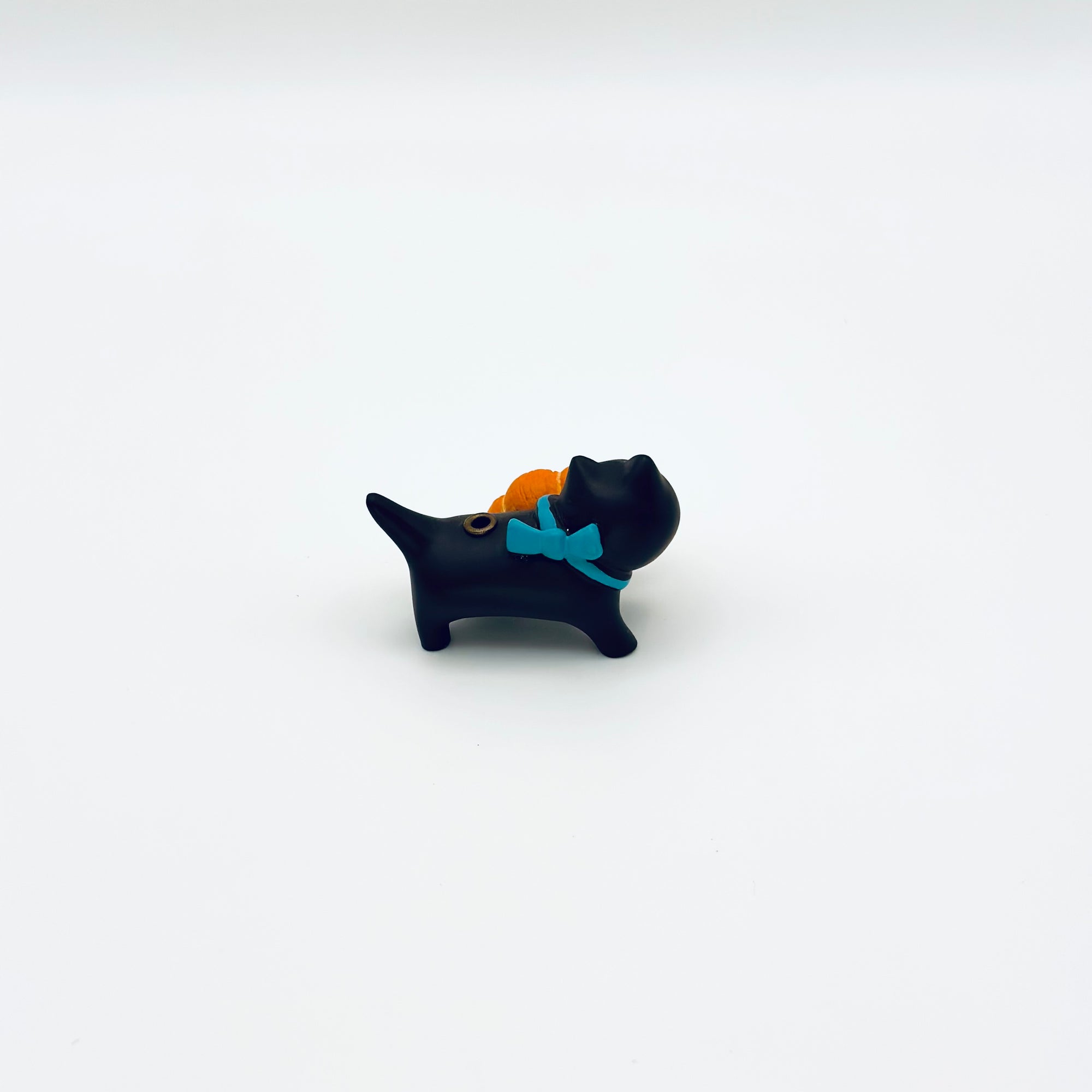 Back view of resin-crafted cat and croissant incense holder with turquoise bow.