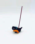 Cat and croissant resin incense holder shown in use with an upright burning incense stick.