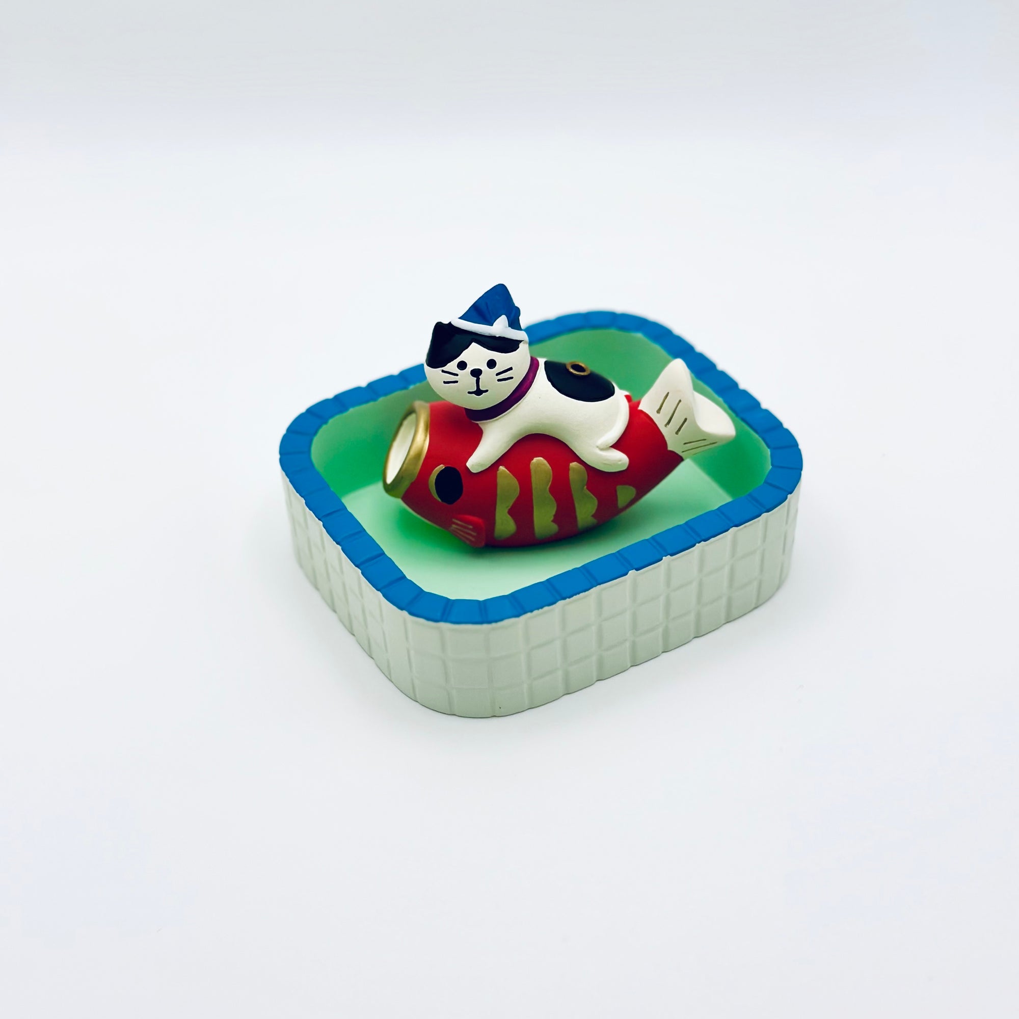 Cat and koi incense holder placed inside the Purrfect Ash Tub for ash collection.