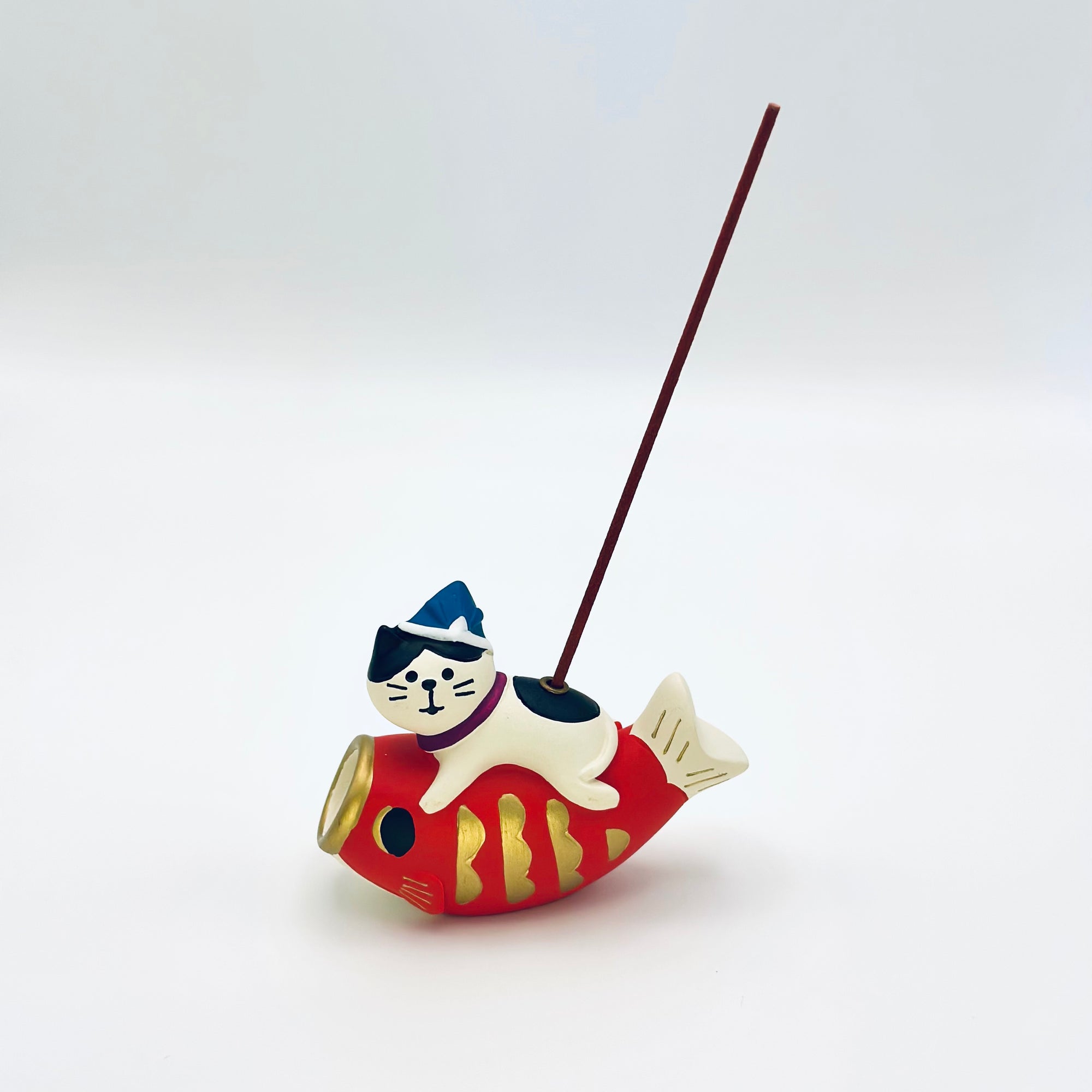 Cat and koi incense holder with an incense stick inserted, displayed in a minimalist white background.