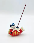 Cat and koi incense holder with an incense stick inserted, displayed in a minimalist white background.