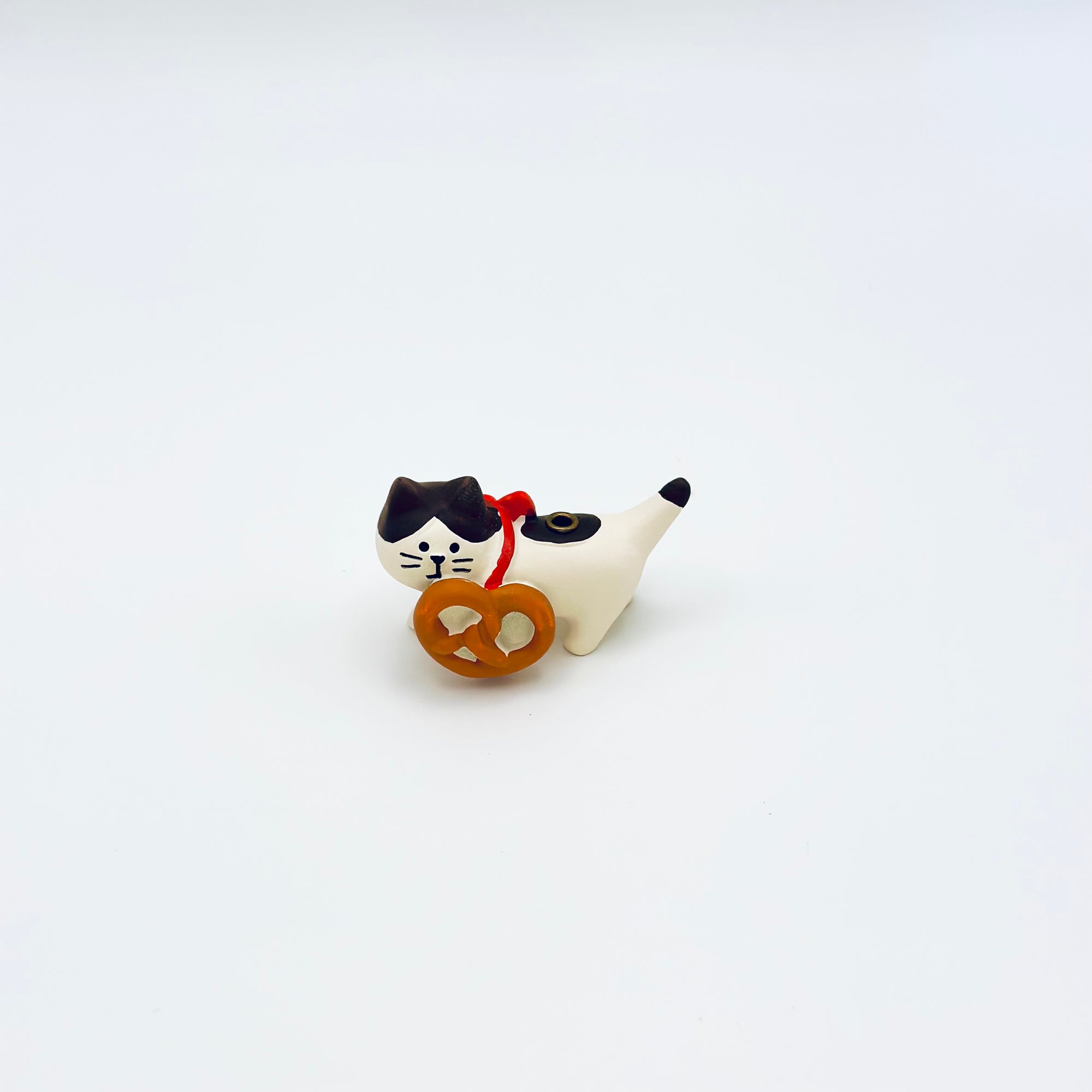 Ceramic cat incense holder holding a pretzel-shaped accessory on a white background.