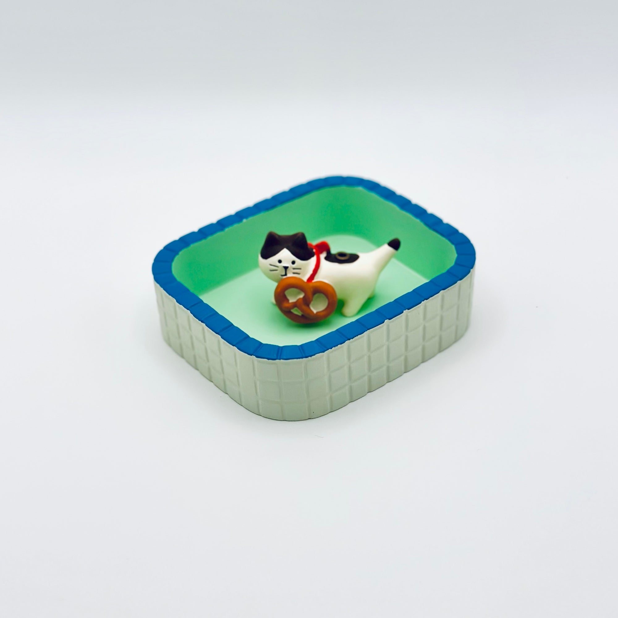 Cat and pretzel incense holder placed inside a mint-green Purrfect Ash Tub.