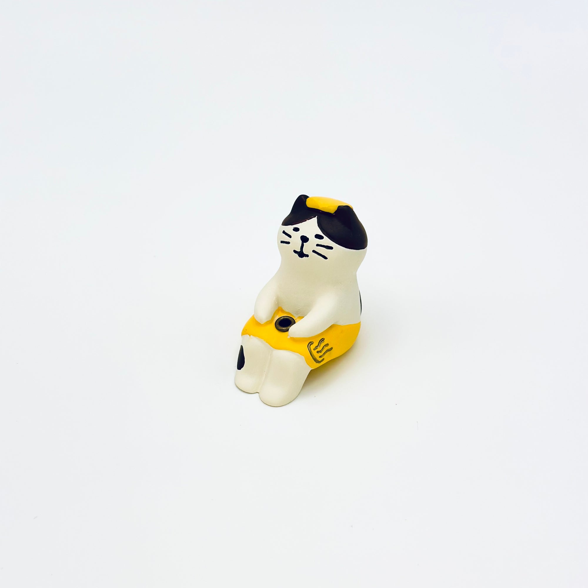 Resin-crafted Cat & Towel Incense Stick Holder shown sitting upright, wearing a yellow towel with a relaxed expression on a clean white background.