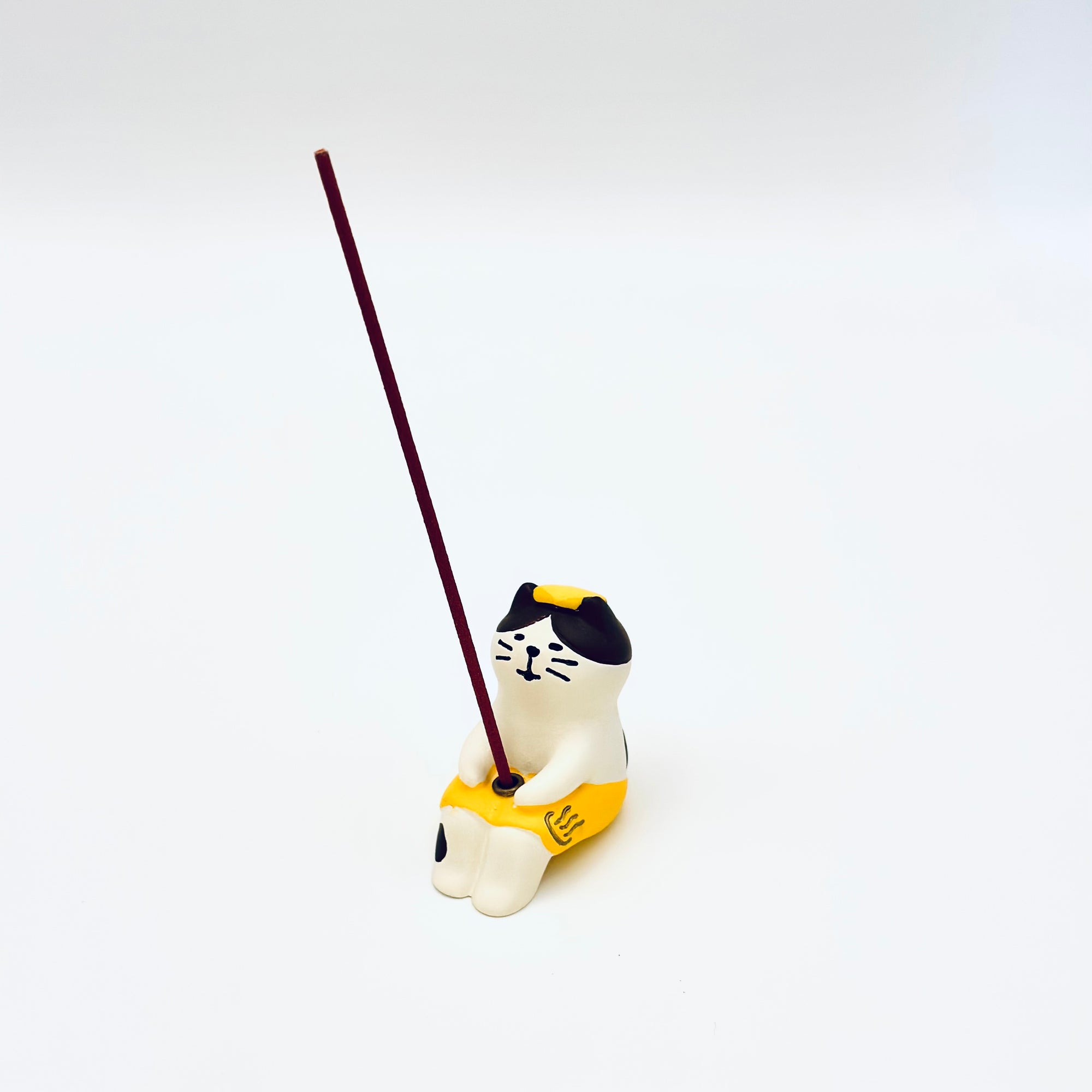 Cat & Towel incense holder in use, holding a vertical incense stick in the center of the resin-crafted figurine.