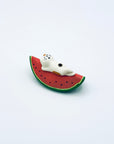 Ceramic cat lounging on a watermelon slice incense holder, displayed on a clean white background.