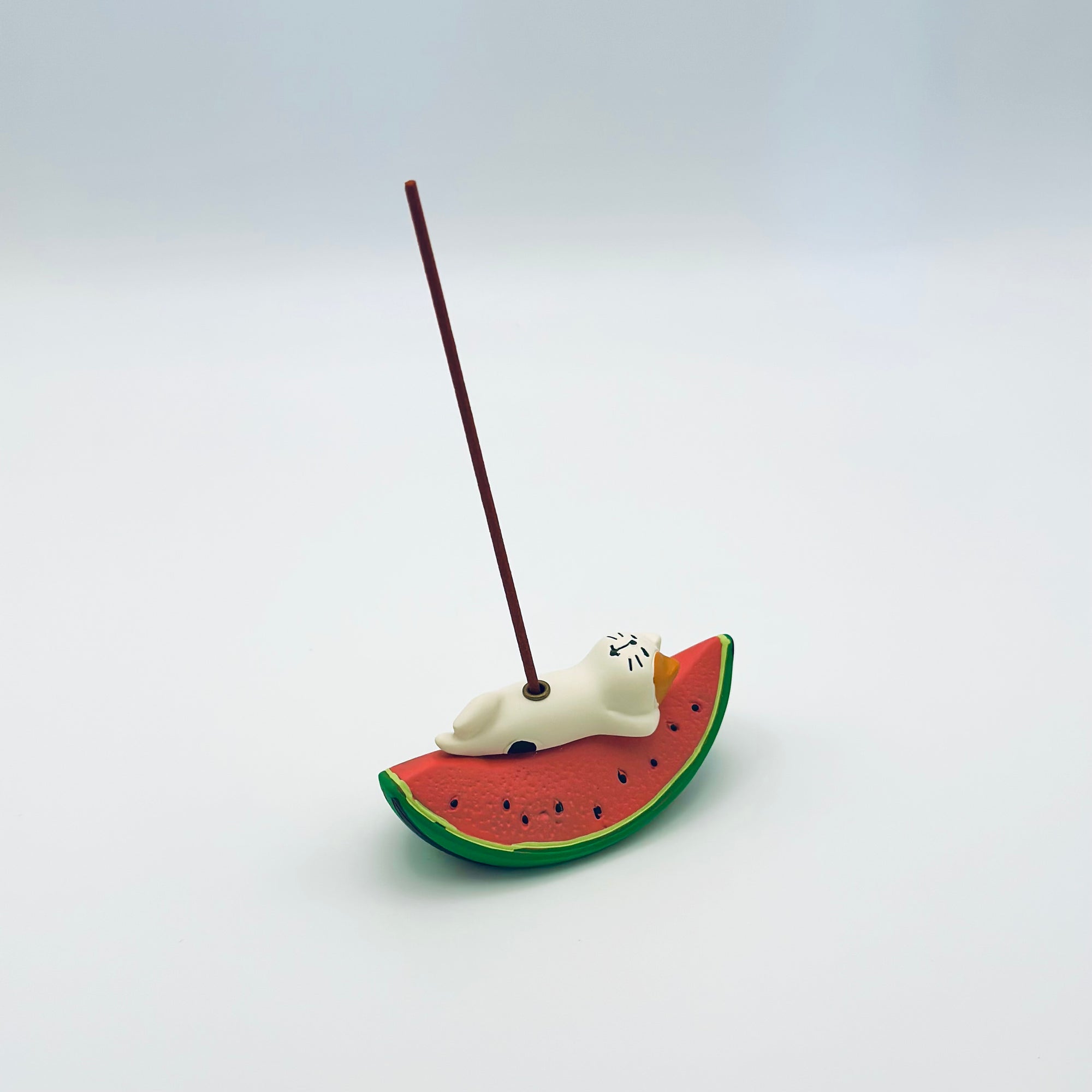 Cat & Watermelon incense holder in use with a lit incense stick standing upright.