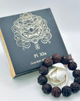 Limited Sacred Edition Guardian Bead Bracelet displayed beside its signature black gift box; handcrafted wooden beads with intricate guardian-carving details.