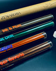 Zen Aroma incense collection close-up showing multiple glass tubes with colorful labels and natural incense sticks, displayed on a dark surface with brand packaging in the background.