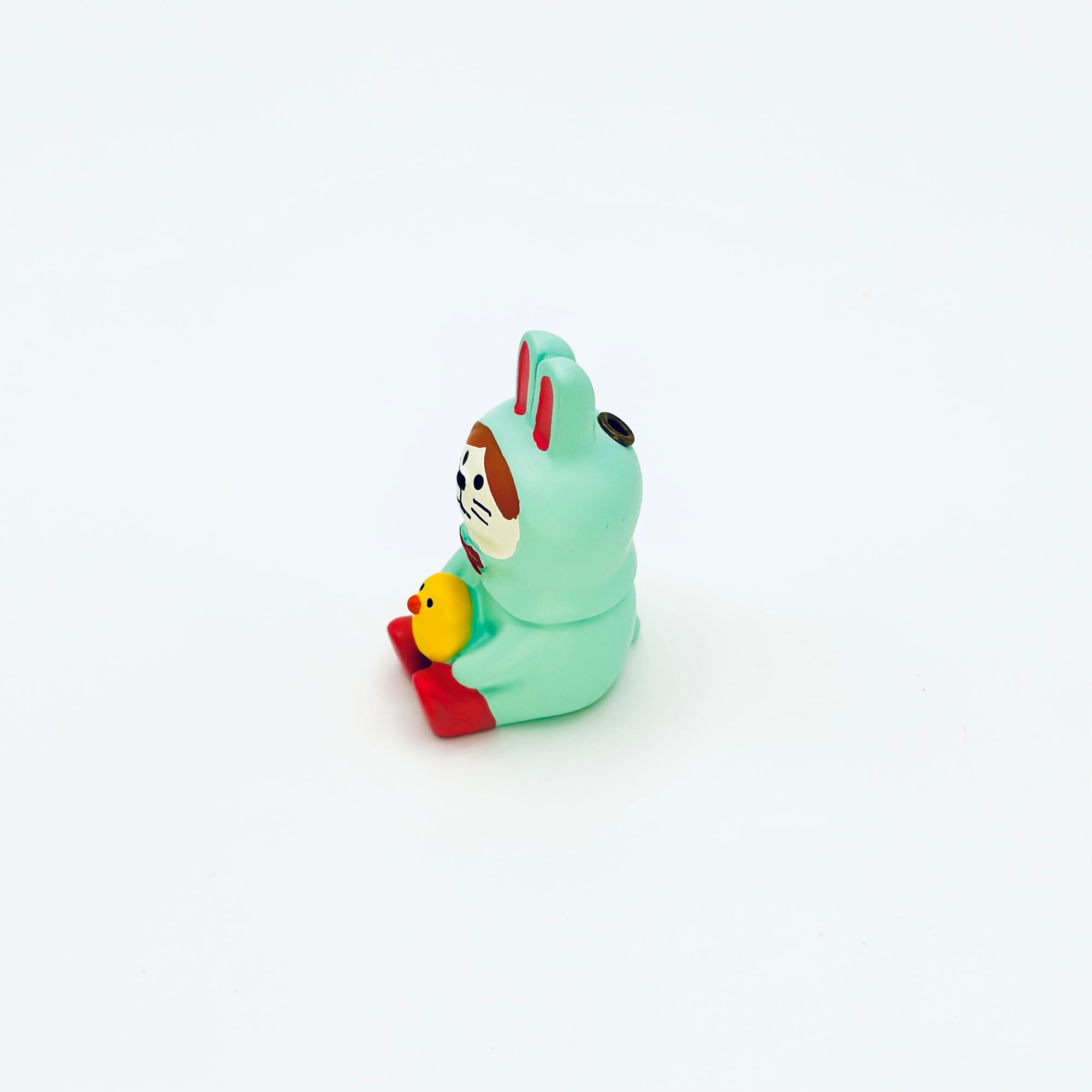 A mint-green bunny resin incense holder holding a small yellow chick, shown from a side angle on a clean white background.