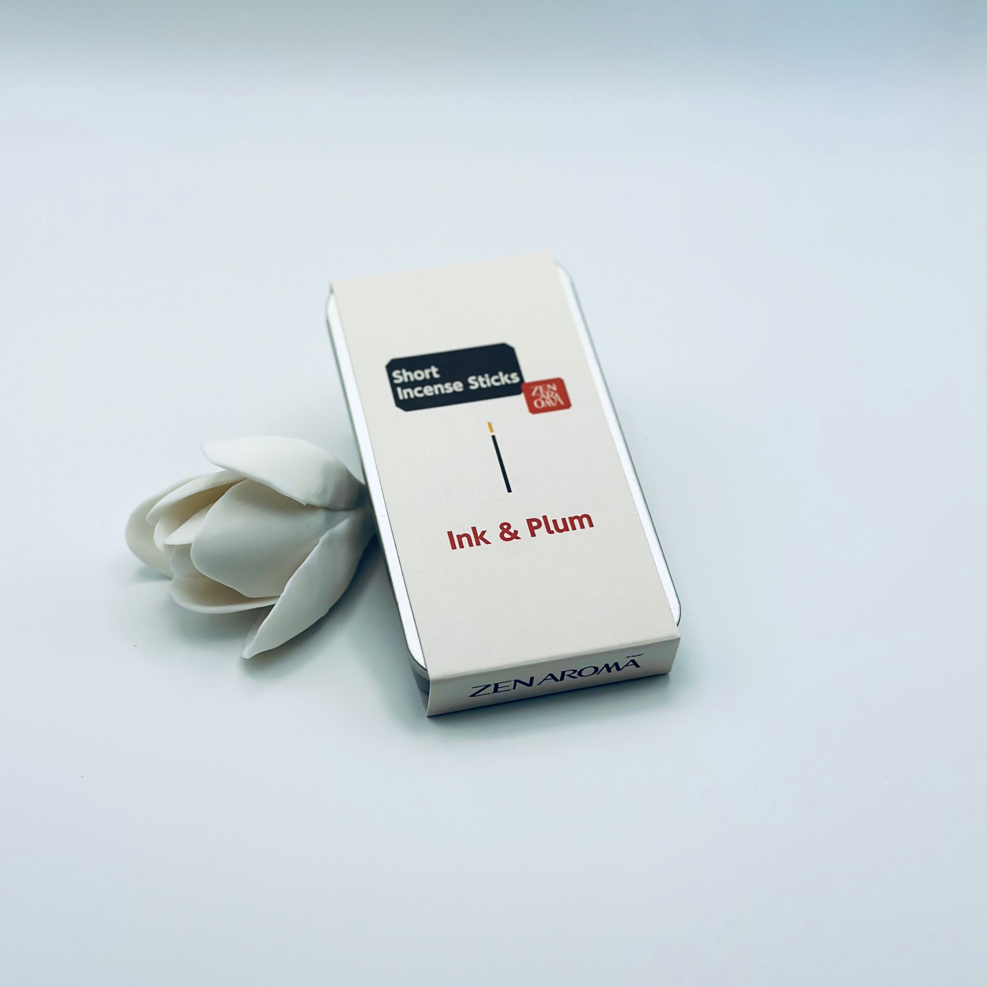 Zen Aroma Ink & Plum To-Go Incense Kit in beige metal box, styled with a white flower on a clean white background, showcasing minimalist packaging design.