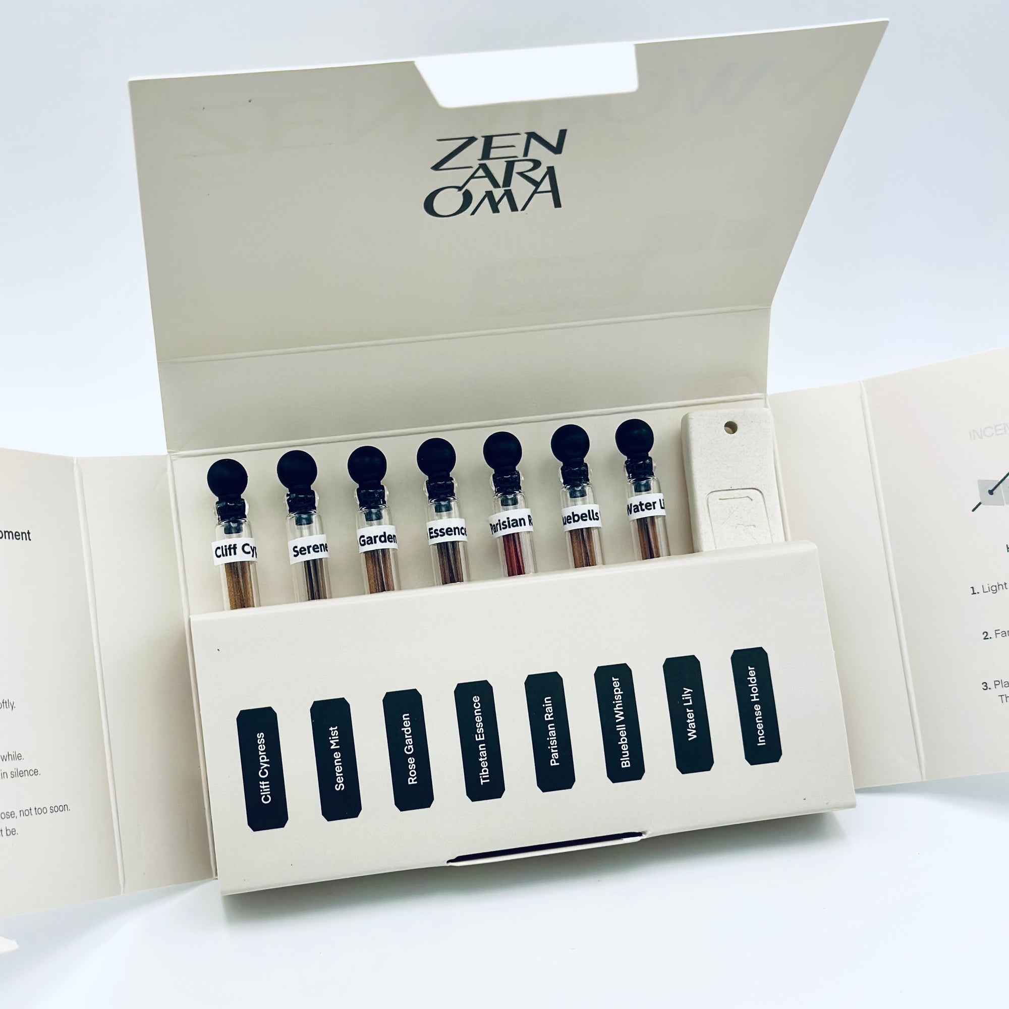 Zen Aroma “Serenity Sampler” open box displaying seven short incense blends in glass vials and a minimalist incense holder, arranged neatly inside cream-colored packaging on a white background.