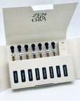 Zen Aroma “Serenity Sampler” open box displaying seven short incense blends in glass vials and a minimalist incense holder, arranged neatly inside cream-colored packaging on a white background.
